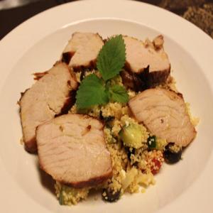Greek style grilled pork loin served over roasted garlic and fresh veggie couscous_image