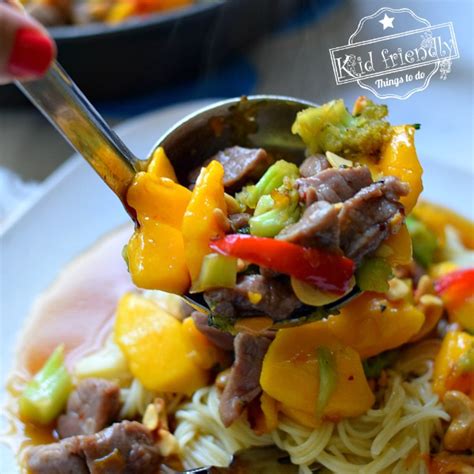 pork-stir-fry-with-mango-served-over-pasta-noodles image